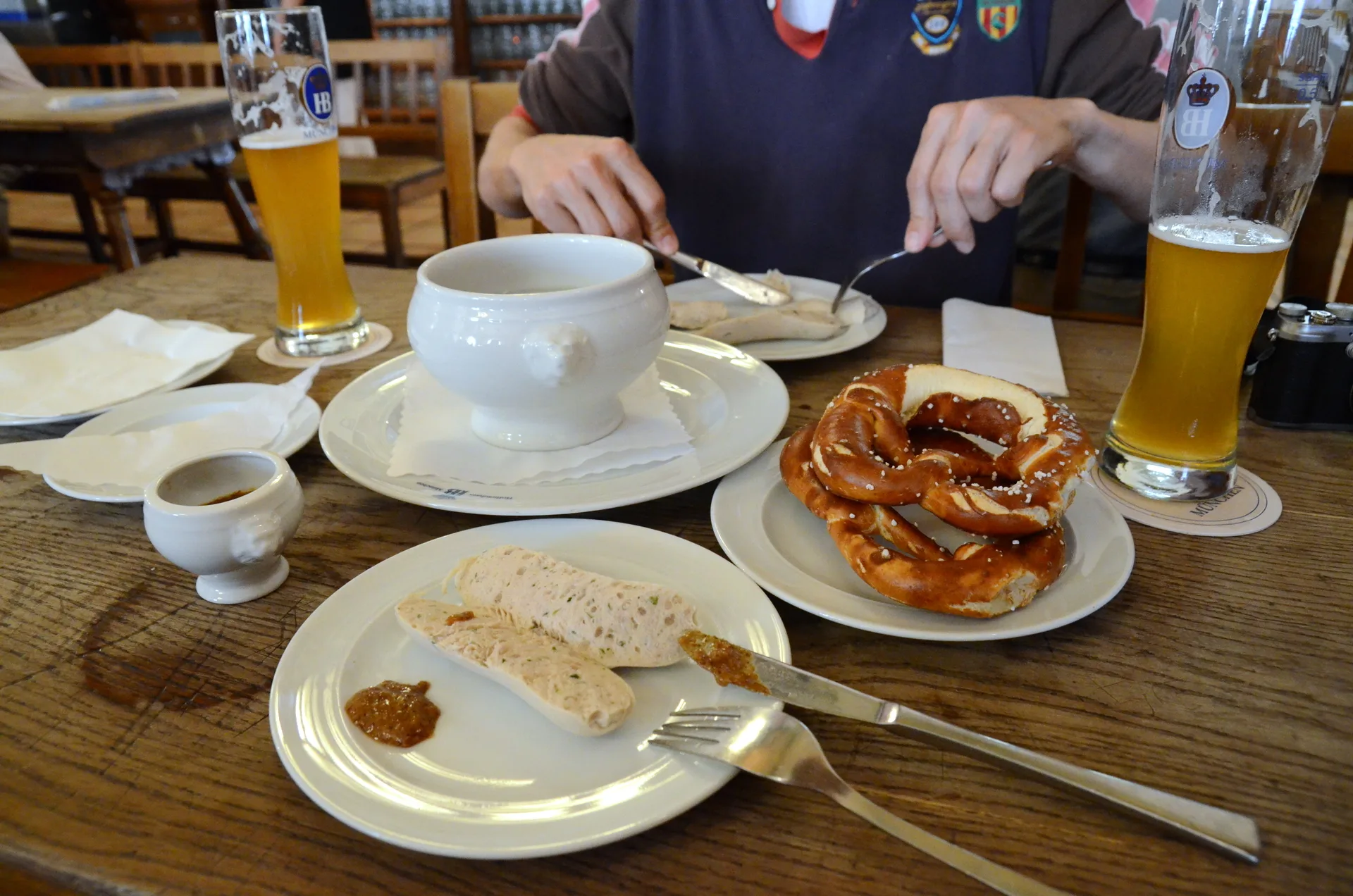 Spécialités culinaires allemandes servies à table : saucisses, bretzel et bière
